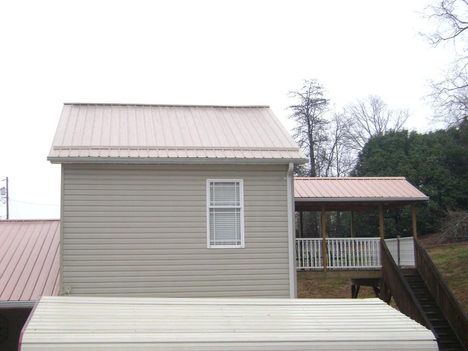 Tan metal roofs on a two story addition and attached porch, from a Roof Replacement job in Montrose